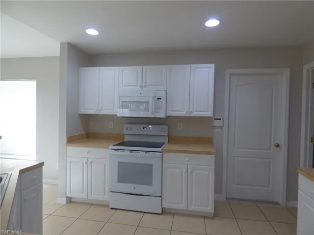 Kitchen featuring white appliances, white cabinets, and light countertops