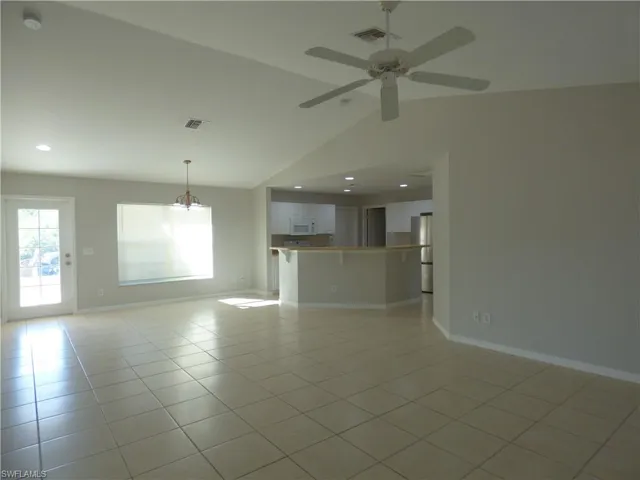 View of Great room with ceiling fan, vaulted ceiling, light tile patterned floors, and chandelier over dining area from lanai!