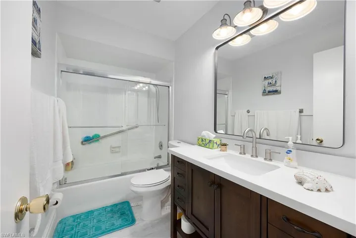 Bathroom featuring vanity and shower / bath combination with glass door