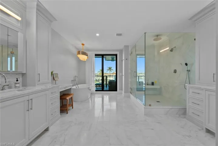 Master Bathroom with a marble finish shower, vanity, a freestanding tub, light marble finish floors, and recessed lighting