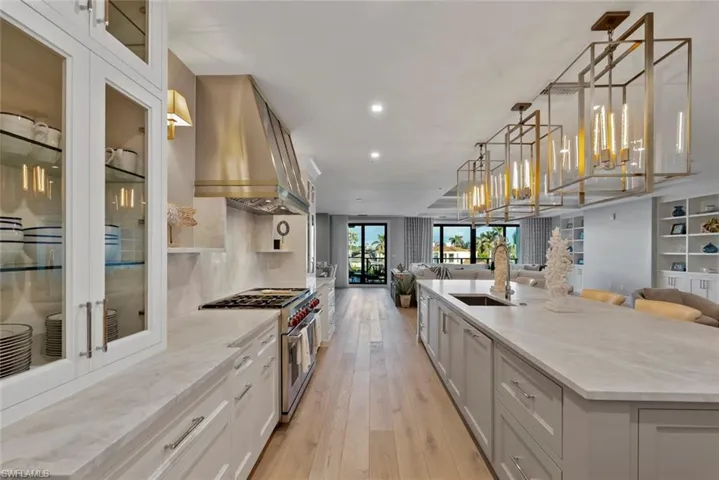 Kitchen featuring light stone counters, custom exhaust hood, a large island, double oven range, and open floor plan