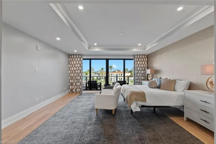 Master Bedroom with access to exterior, light wood-type flooring, recessed lighting, and a raised ceiling