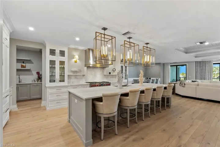 Kitchen featuring a breakfast bar, open shelves, decorative light fixtures, glass insert cabinets, and open floor plan
