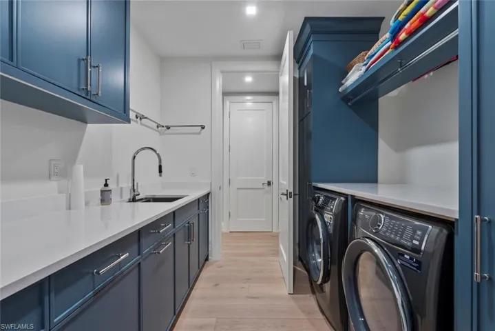 Laundry area with light wood finished floors, washer and clothes dryer, cabinet space, and recessed lighting