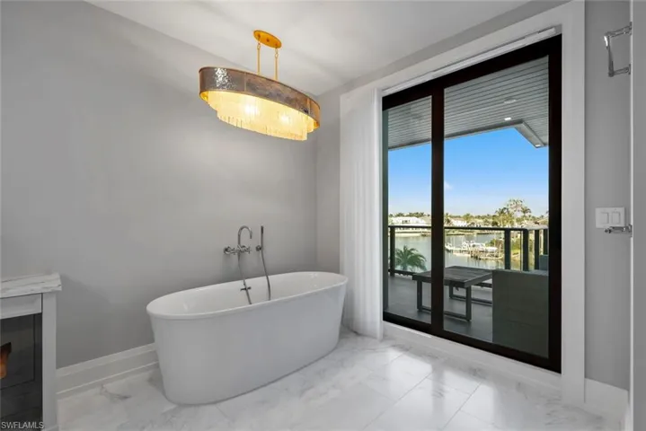 Master Bathroom with a water view, a soaking tub, and light marble finish floors