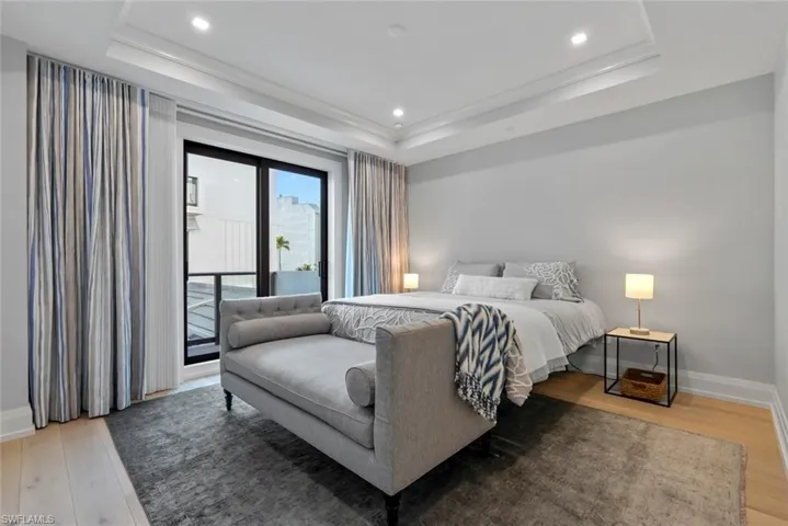 Master Bedroom with light wood-style floors, access to outside, a tray ceiling, and recessed lighting