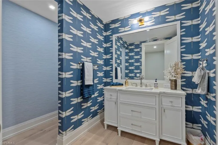 Bathroom with light wood-type flooring, vanity, and wallpapered walls