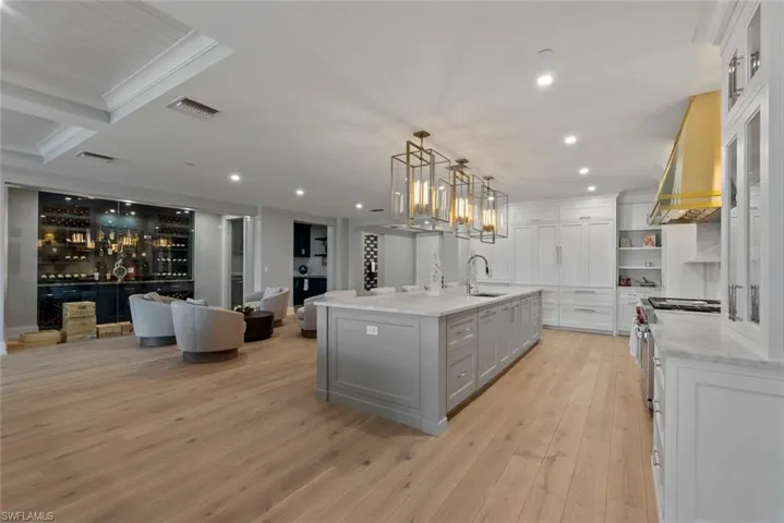 Kitchen with decorative light fixtures, gray cabinets, premium range hood, open floor plan, and high end stove