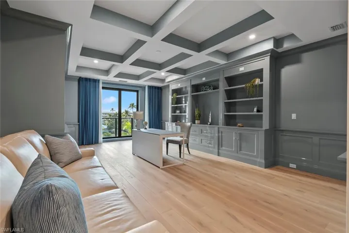 Office area with Gulf view featuring coffered ceiling, beam ceiling, light wood finished floors, and a decorative wall
