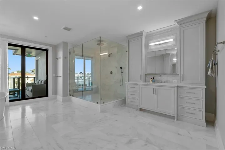Bathroom featuring vanity, a marble finish shower, light marble finish floors, recessed lighting, and a freestanding bath