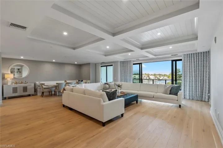 Living room with beamed ceiling, light wood-style flooring, coffered ceiling, and recessed lighting