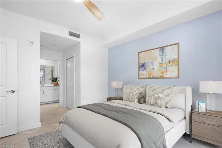 Bedroom featuring light tile patterned floors, ensuite bath, a closet, and a ceiling fan