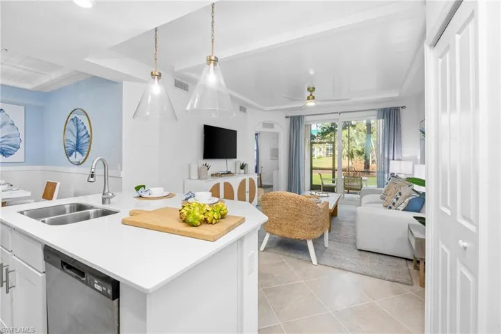 Kitchen with stainless steel dishwasher, open floor plan, white cabinetry, a center island with sink, and light tile patterned floors