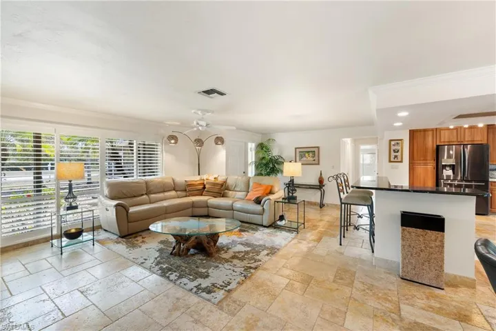 Living room with ceiling fan, crown molding, travertine tile floors