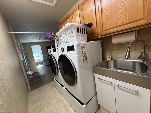 Laundry area with new  washer and dryers, cabinet space, and laundry sink, plenty of storage