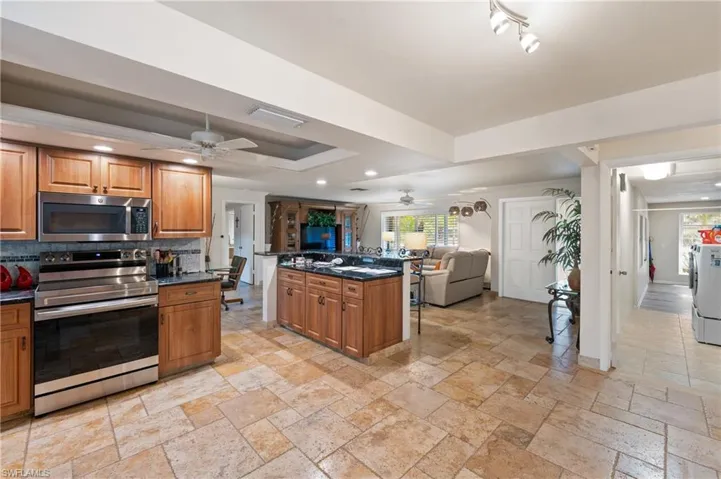 Kitchen featuring stainless steel appliances, wood finish cabinets, open floor plan, ceiling fan, and recessed lighting
