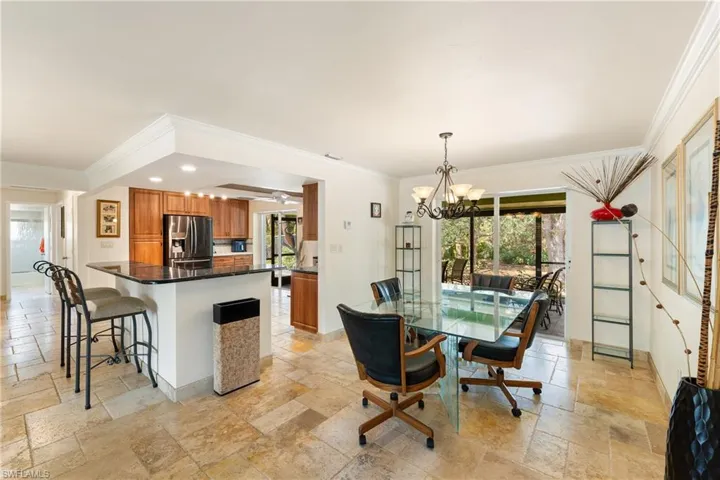 Dining room featuring travertine tile flooring, hanging lights, ornamental molding, and plenty of natural light