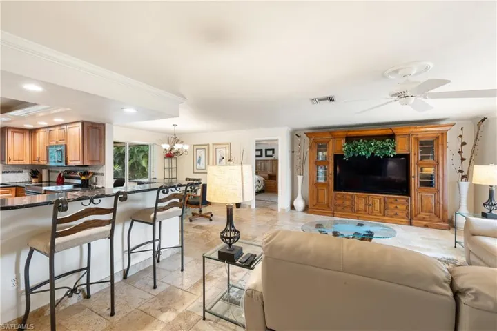 Living room with ornamental molding, ceiling fan, hanging lights, and stone  flooring