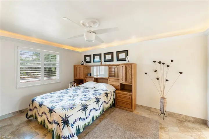 Bedroom with stone tile flooring, crown molding, and ceiling fan