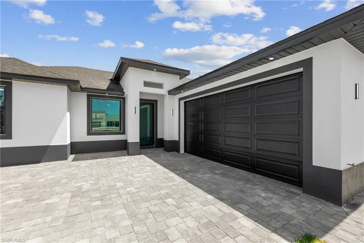 Doorway to property with a garage, decorative driveway, and stucco siding