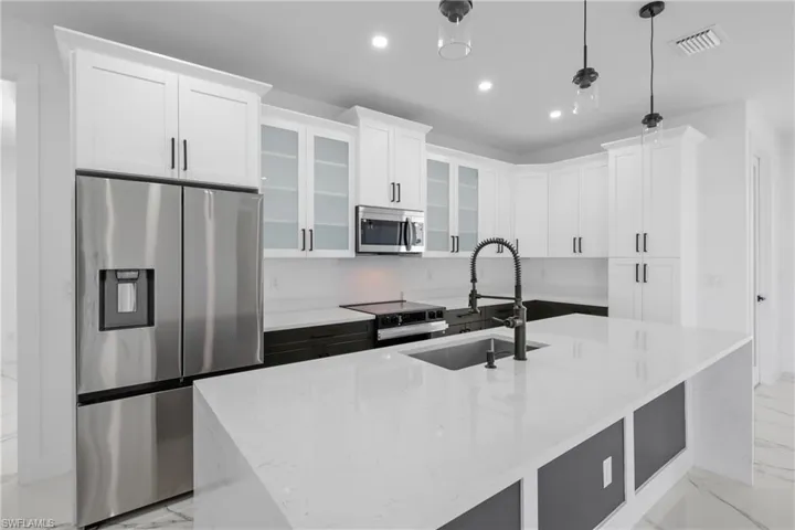 Kitchen with visible vents, marble finish floor, a kitchen island with sink, appliances with stainless steel finishes, and a sink