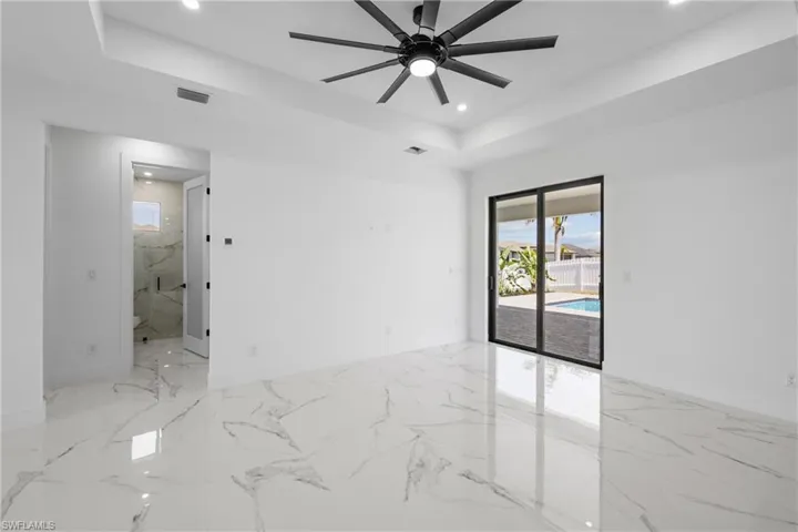 Empty room featuring a tray ceiling, recessed lighting, marble finish floor, visible vents, and ceiling fan