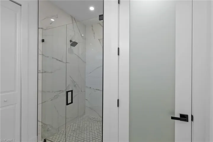 Full bathroom with a marble finish shower and recessed lighting