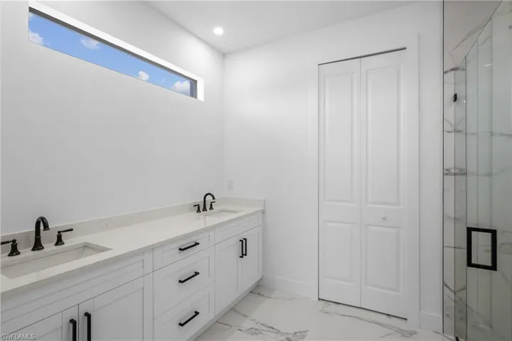 Bathroom featuring a marble finish shower, marble finish floor, a sink, and recessed lighting