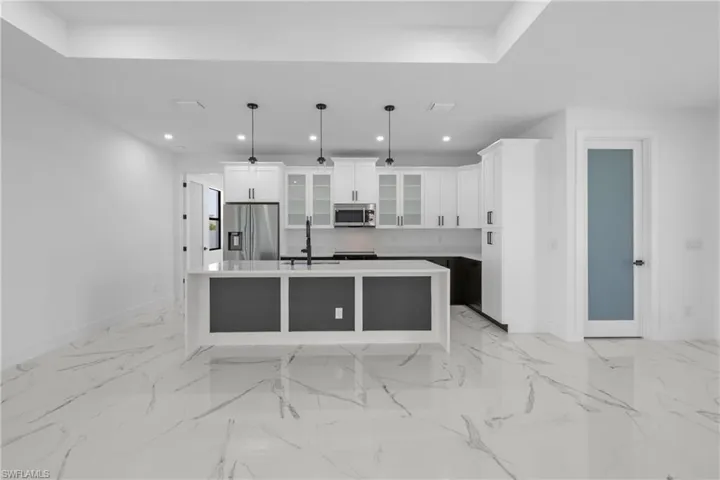 Kitchen with stainless steel appliances, recessed lighting, glass insert cabinets, white cabinetry, and a sink