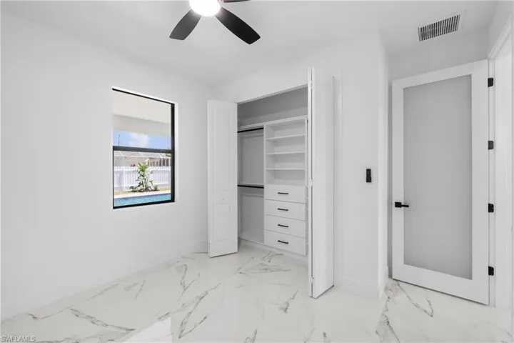 Unfurnished bedroom with a closet, visible vents, baseboards, marble finish floor, and a ceiling fan