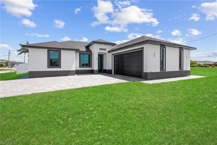 Prairie-style home with a front yard, stucco siding, an attached garage, and driveway