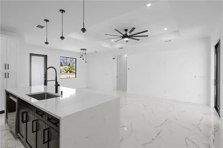 Kitchen featuring marble finish floor, a tray ceiling, a sink, and recessed lighting