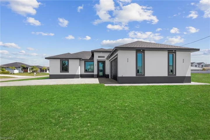 Rear view of house featuring a garage, stucco siding, and a lawn