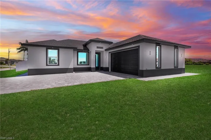 Prairie-style home featuring stucco siding, roof with shingles, an attached garage, decorative driveway, and a lawn