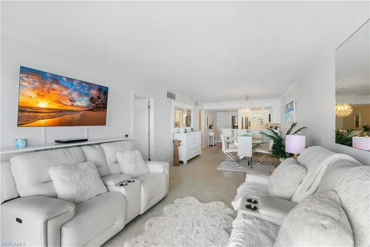 Living area featuring crown molding and suspended lighting