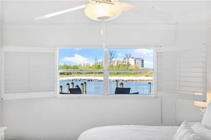 Bedroom with ornamental molding, a ceiling fan, and a water view