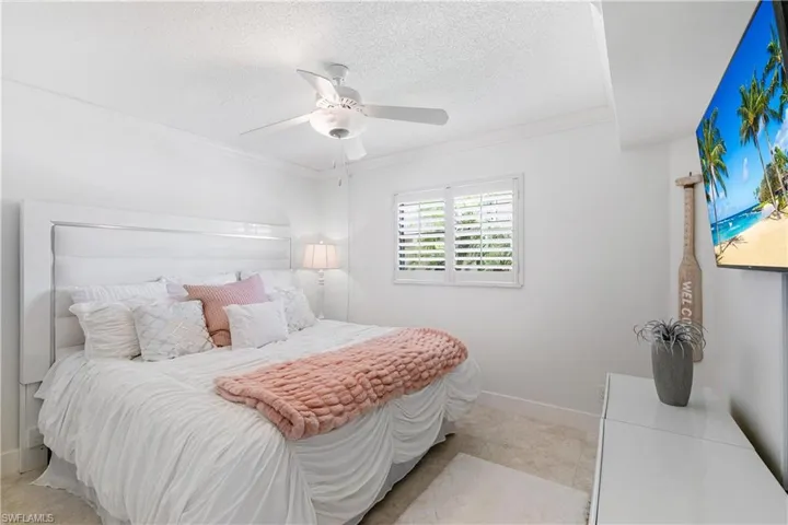 Bedroom with a textured ceiling, ceiling fan, and ornamental molding
