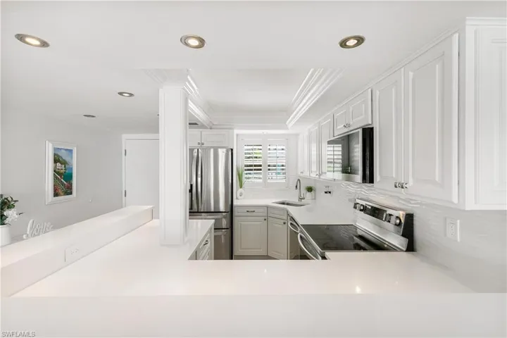 Kitchen featuring stainless steel appliances, recessed lighting, white cabinetry, crown molding, and backsplash
