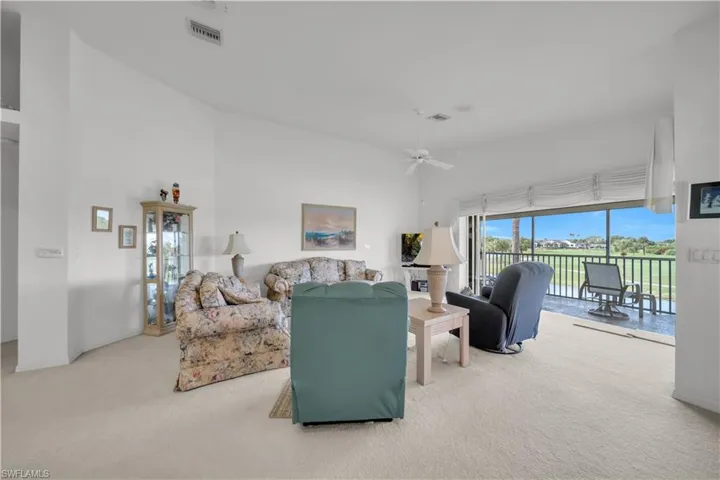 Living room with light colored carpet, a ceiling fan, and a high ceiling