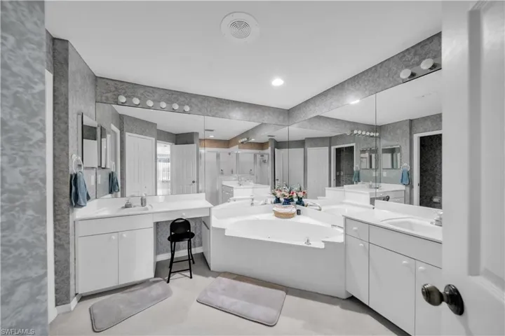 Bathroom featuring two vanities, a garden tub, recessed lighting, and wallpapered walls