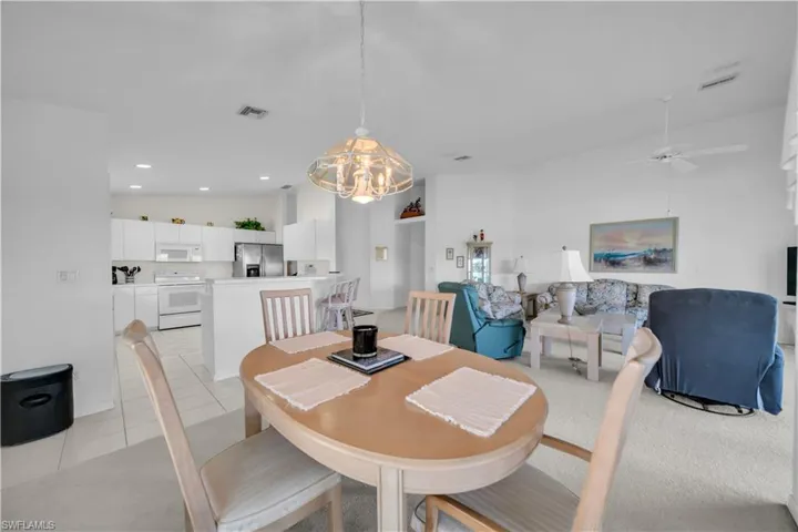 Dining area featuring ceiling fan, hanging lights, light tile patterned floors, and a high ceiling