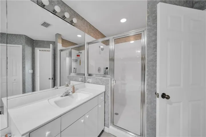 Bathroom featuring vanity, a stall shower, recessed lighting, and wallpapered walls