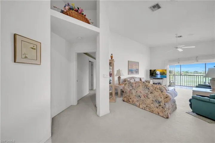 Living room with a high ceiling, ceiling fan, and light carpet