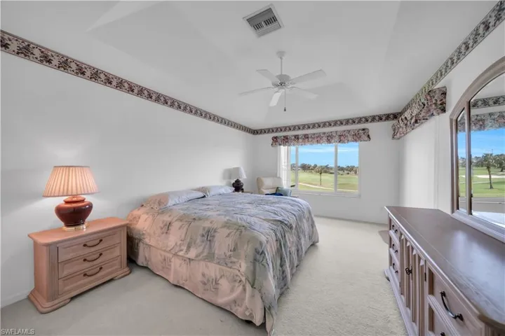 Bedroom featuring light colored carpet, ceiling fan, and golf course view