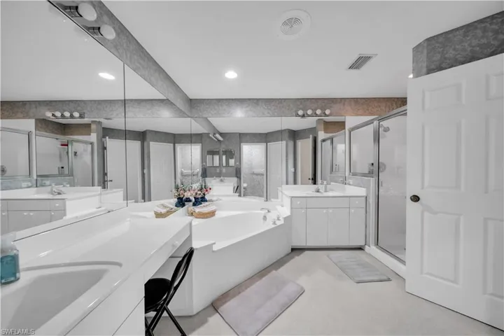 Bathroom featuring two vanities, a bath, a shower stall, and recessed lighting