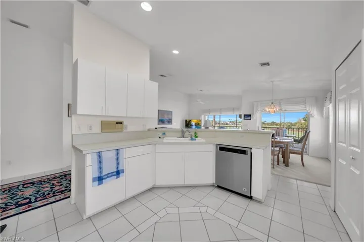 Kitchen with light countertops, a peninsula, white cabinetry, dishwasher, and pendant lighting