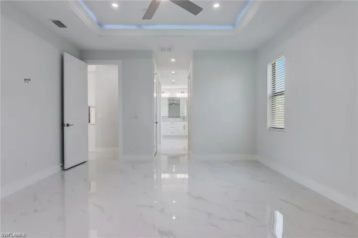 Unfurnished room featuring a tray ceiling, ceiling fan, and ornamental molding