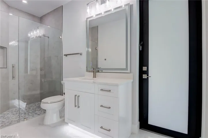 Bathroom featuring vanity, an enclosed shower, and toilet