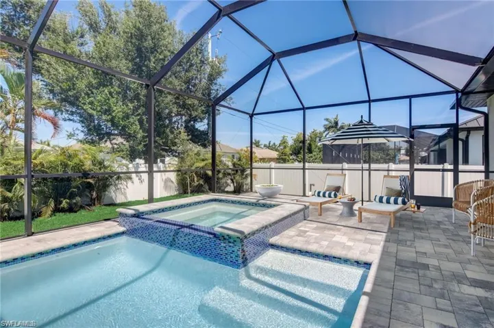 View of pool featuring a lanai, a patio area, and an in ground hot tub