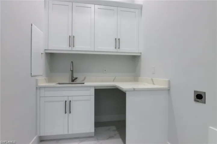 Laundry room featuring hookup for an electric dryer, cabinets, and sink